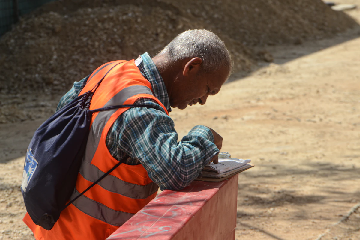 A contractor in a high-visibility vest reviewing paperwork at a job site in daylight